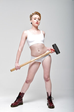 Pale-skinned floozy with short red hair and tongue piercing holds sledgehammer