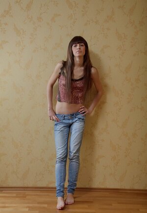 Delightful 18-19 year old Licky Lex unhurriedly takes off jeans to pose undressed near wall
