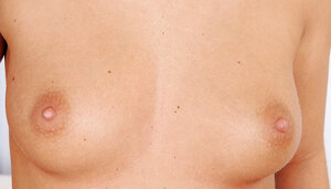 Frisky blond broad with yummy boobs sensually poses undressed by the couch